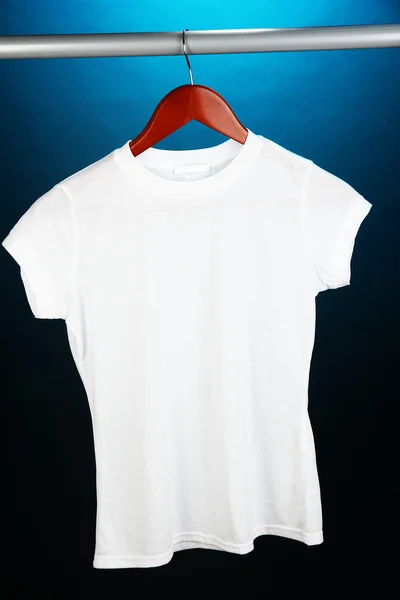 Weißes T-Shirt auf Kleiderbügel auf blauem Hintergrund — Stockfoto