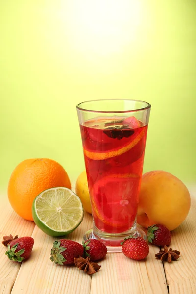 Sangria refrescante em vidro com frutas, na mesa de madeira, no fundo verde — Fotografia de Stock