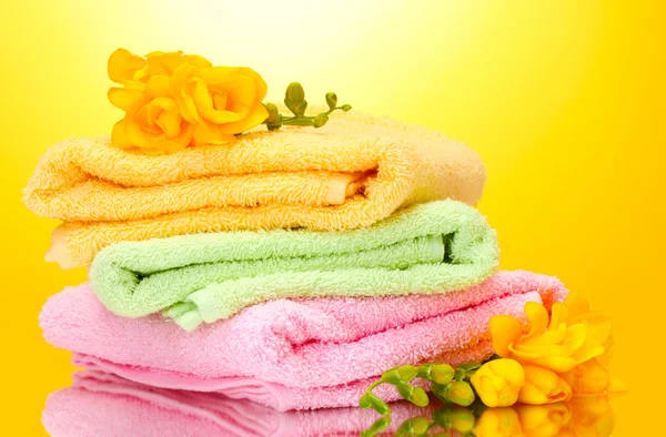 Kleurrijke handdoeken en bloemen op gele achtergrond — Stockfoto