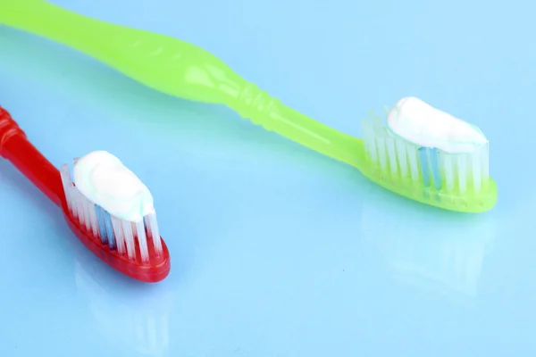Escovas de dentes com pasta no fundo azul — Fotografia de Stock
