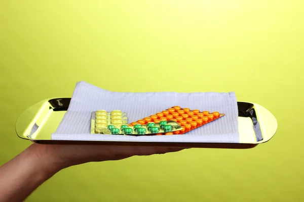 Ręka trzyma tacę z tabletek na zielonym tle — Zdjęcie stockowe