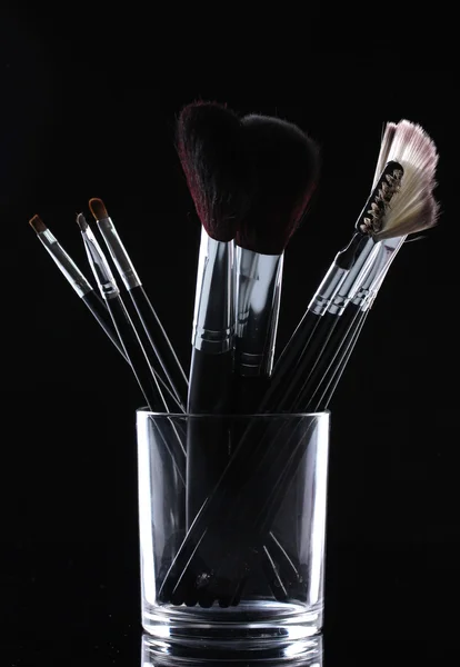 Make-up brushes in glass cup on grey background — Stock Photo, Image