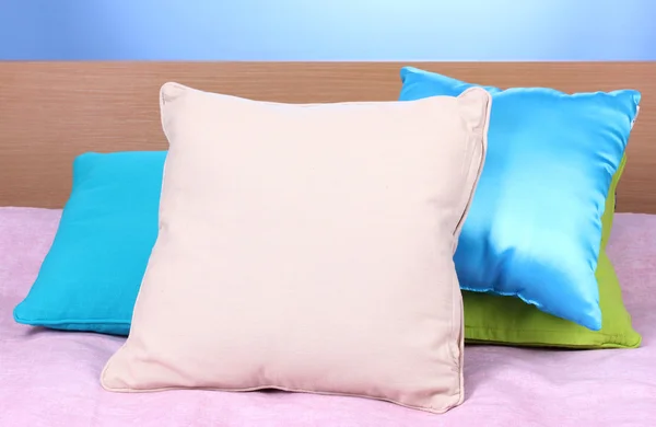 Jasne poduszki na łóżku na niebieskim tle — Zdjęcie stockowe