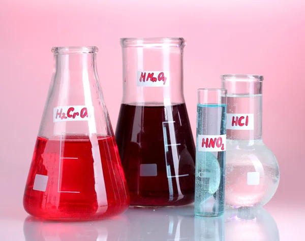 Tubes à essai avec divers acides et produits chimiques sur fond rose — Photo