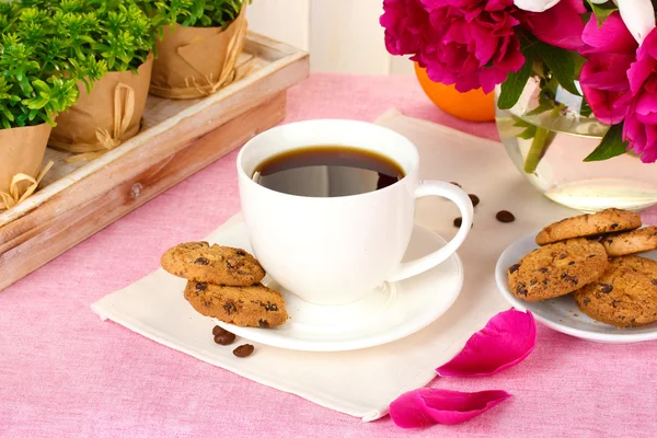 Cup of coffee, cookies, orange and flowers on table in cafe — Stock Photo, Image