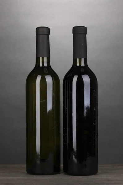 Gri zemin üzerine ahşap masa üzerinde büyük şarap şişeleri — Stok fotoğraf