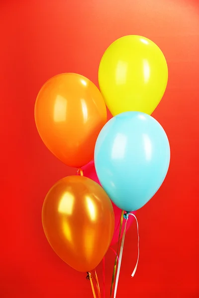 Bunte Luftballons auf rotem Hintergrund — Stockfoto