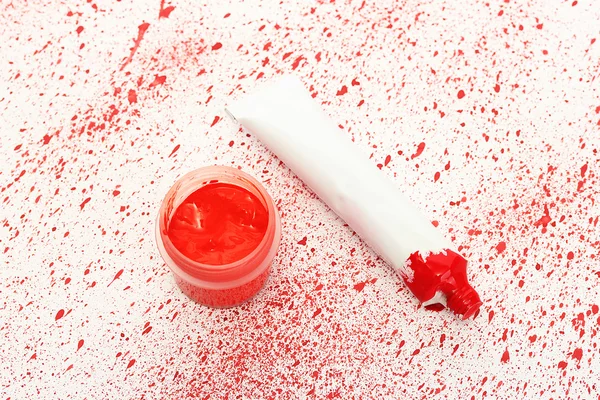 Pot met rode gouache en buis met rode waterverf op achtergrond van rode spray close-up — Stockfoto