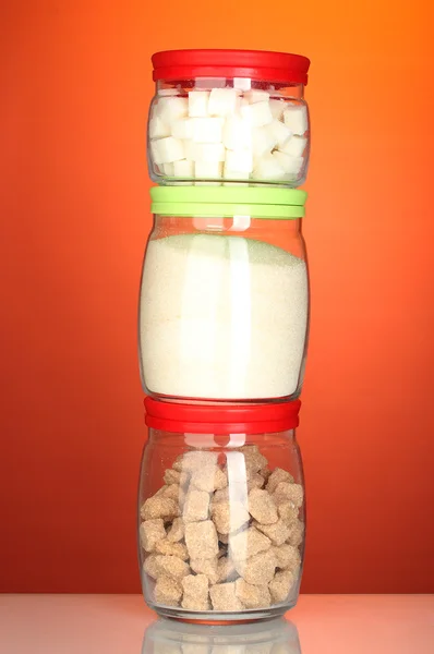 Pots avec morceau de sucre de canne brun, sucre de cristal blanc et sucre en morceaux blanc sur fond coloré — Photo