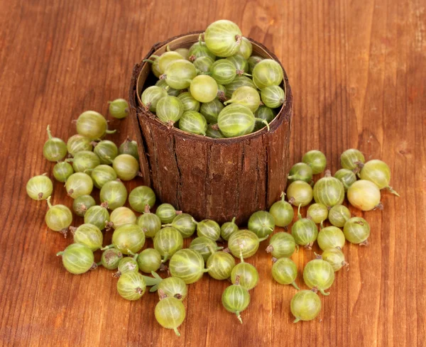 Uva spina verde in tazza di legno su sfondo di legno — Foto Stock