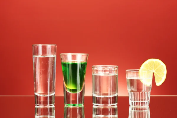 Различные алкогольные напитки на красном фоне — стоковое фото