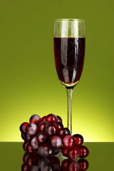 Ett glas vin och druvor på grönt backgrund närbild — Stockfoto