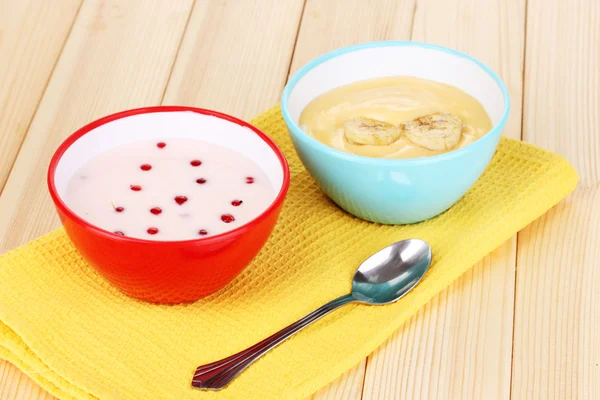 Yogurt with banana and redcurrant on wooden table — Stock Photo, Image