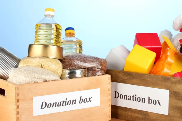 Scatola di donazione con cibo e giocattoli per bambini su sfondo blu primo piano — Foto Stock
