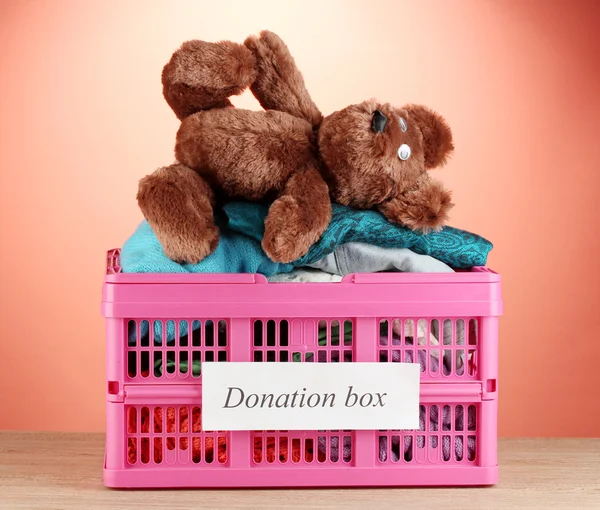 Spendenbox mit Kleidung auf rotem Hintergrund in Großaufnahme — Stockfoto