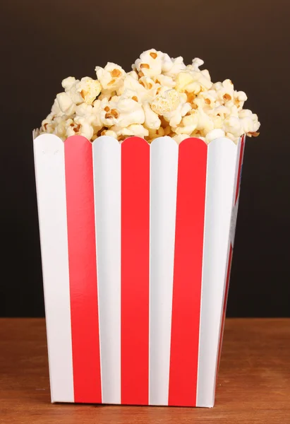 Klasický krabice popcornu na dřevěný stůl na hnědé pozadí — Stock fotografie