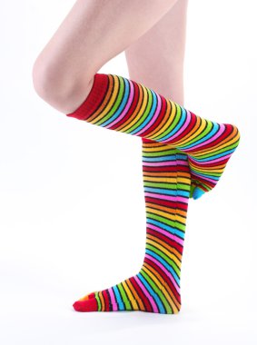 Female legs in colorful striped socks isolated on white clipart