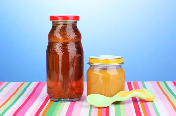 Słoik przecieru dziecka i sok z łyżką serwetka na niebieskim tle — Zdjęcie stockowe
