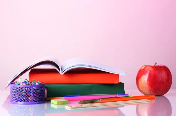 Состав книг, канцелярских принадлежностей и яблока на красочном фоне — стоковое фото