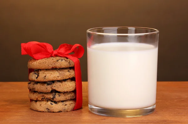 ब्राउन पृष्ठभूमि पर लकड़ी की मेज पर दूध और कुकीज़ का ग्लास — स्टॉक फ़ोटो, इमेज