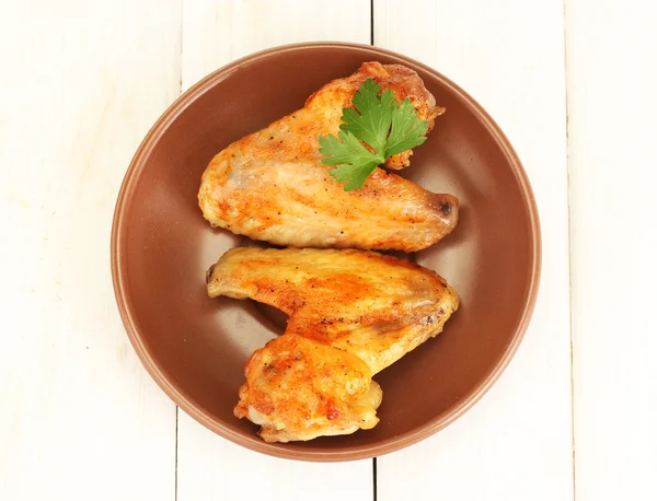 Roasted chicken wings with parsley in the plate on white wooden background close-up — Stock Photo, Image