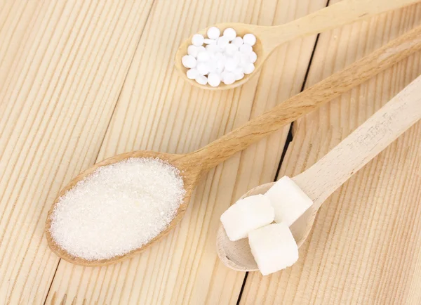 Sødemiddel og hvidt sukker i skeer på træbaggrund - Stock-foto