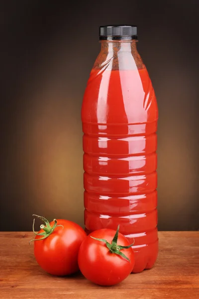 Succo di pomodoro in bottiglia su tavolo di legno su sfondo marrone — Foto Stock