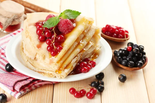 Deliciosos panqueques con bayas, mermelada y miel en la mesa de madera — Foto de Stock