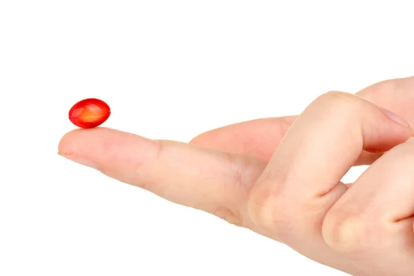 Жіноча рука тримає червону таблетку на білому тлі крупним планом — стокове фото