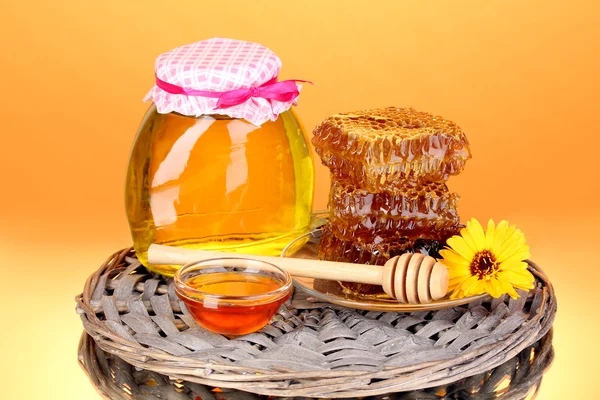 Pot met honing en honingraat op oranje achtergrond — Stockfoto