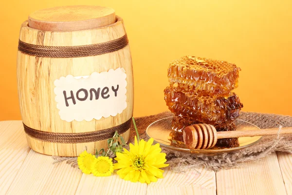 Cañón de miel y panal sobre mesa de madera sobre fondo naranja — Foto de Stock
