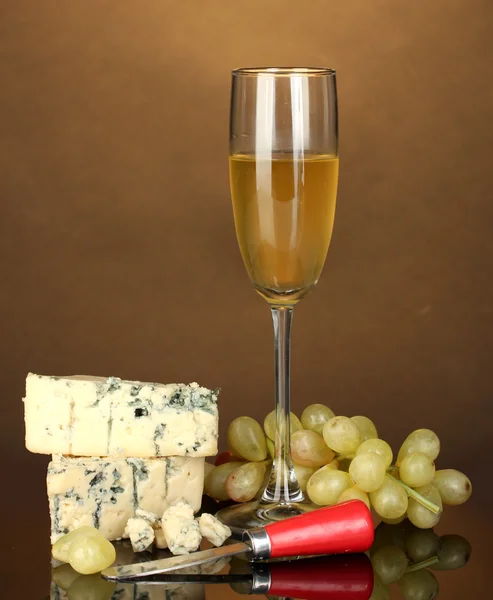 Cheese with mold and goblet of wine on brown background close-up — Stock Photo, Image