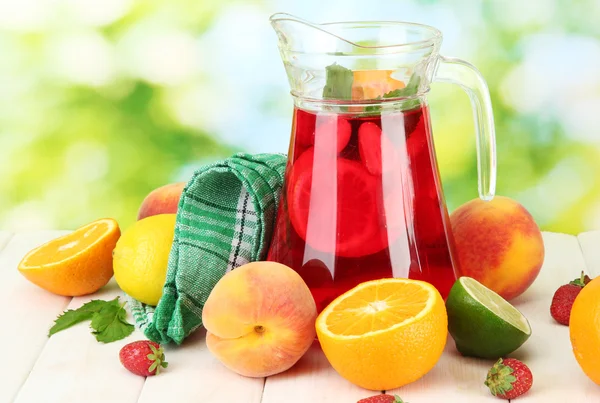 Sangria in jar with fruits, on wooden table, on green background — Stock Photo, Image