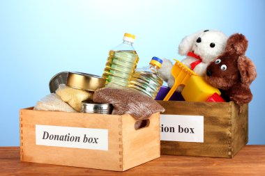 Donation box with food and children's toys on blue background close-up clipart