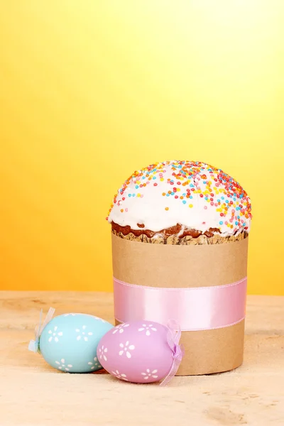Vackra påsk kaka med ägg på träbord på gul bakgrund — Stockfoto