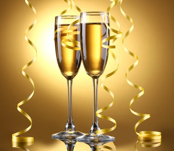 Copas de champán y serpentina sobre fondo amarillo — Foto de Stock