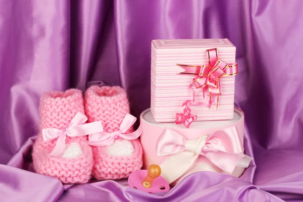 Stivali rosa bambino, ciuccio, regali su sfondo di seta — Foto Stock