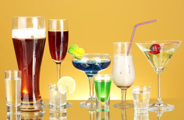 Szeroki wybór napojów alkoholowych na żółtym tle — Zdjęcie stockowe