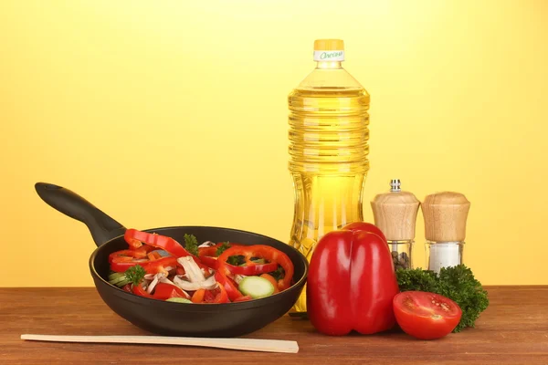 Frying pan with vegetables on yellow background — Stock Photo, Image