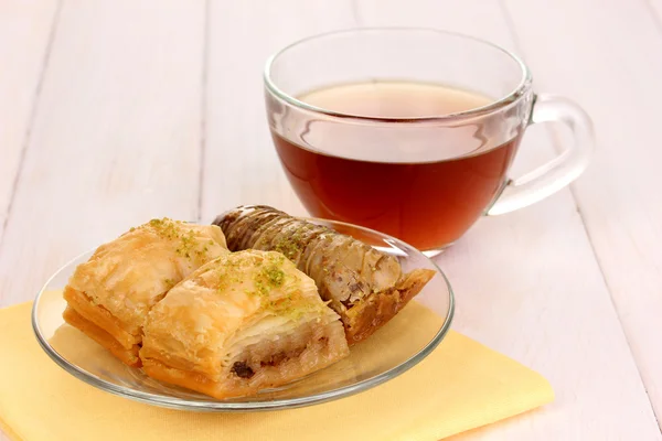 Sweet baklava on plate with tea on wooden background — Stock Photo, Image