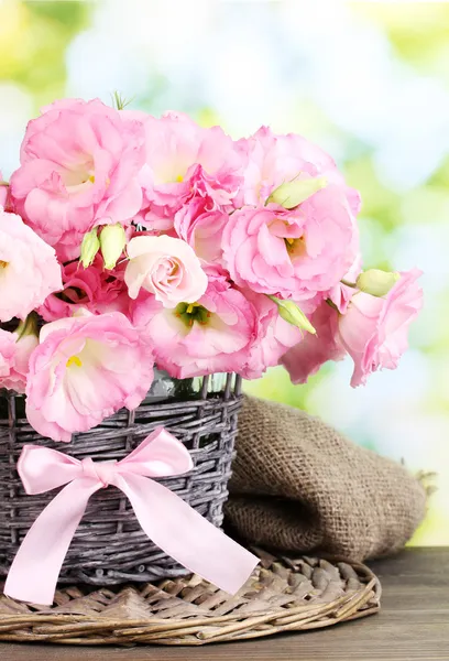 녹색 배경에 나무 테이블에 고리 버들 세공 꽃병에 eustoma 꽃의 꽃다발 — 스톡 사진