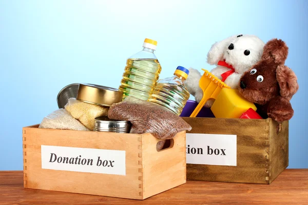 Caixa de doação com alimentos e brinquedos infantis em fundo azul close-up — Fotografia de Stock