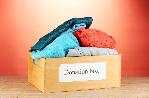 Коробка подарков с одеждой на красном фоне крупным планом — стоковое фото