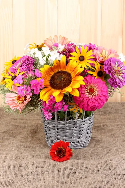 Beautiful bouquet of bright flowers on sacking on wooden background — Stock Photo, Image