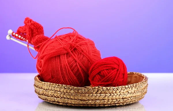 Red knittings yarns in basket on purple background — Stock Photo, Image