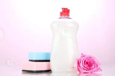 Dishwashing liquid with sponges and flower on pink background clipart