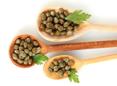 Green capers in wooden spoons on white background close-up clipart