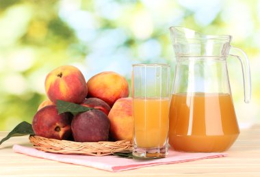 Ripe peaches and juice on wooden table on natural background clipart