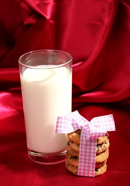 Vaso de leche y galletas sobre fondo de tela roja —  Fotos de Stock