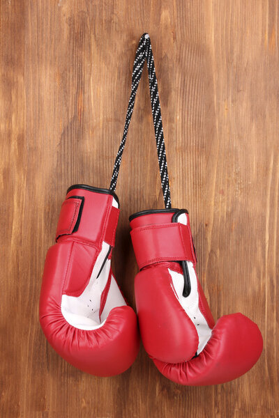 Красные боксерские перчатки висят на деревянном фоне
